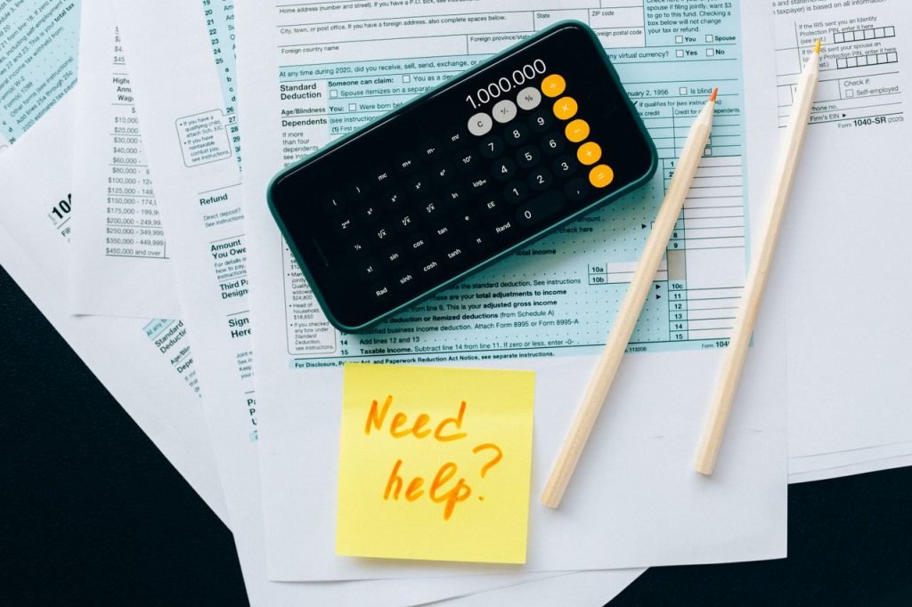 GST/HST Filing Deadlines for Small Businesses in Canada Top view of financial papers with a calculator, pencils, and a note saying 'Need help?' indicating tax or accounting assistance.